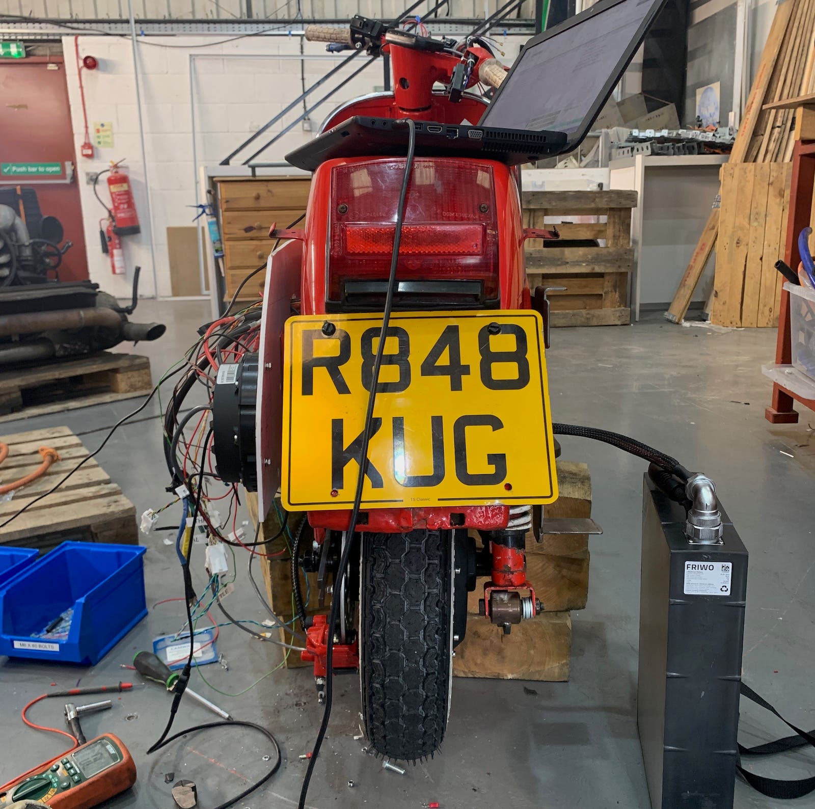 A red scooter with a yellow license plate that says r948 kug