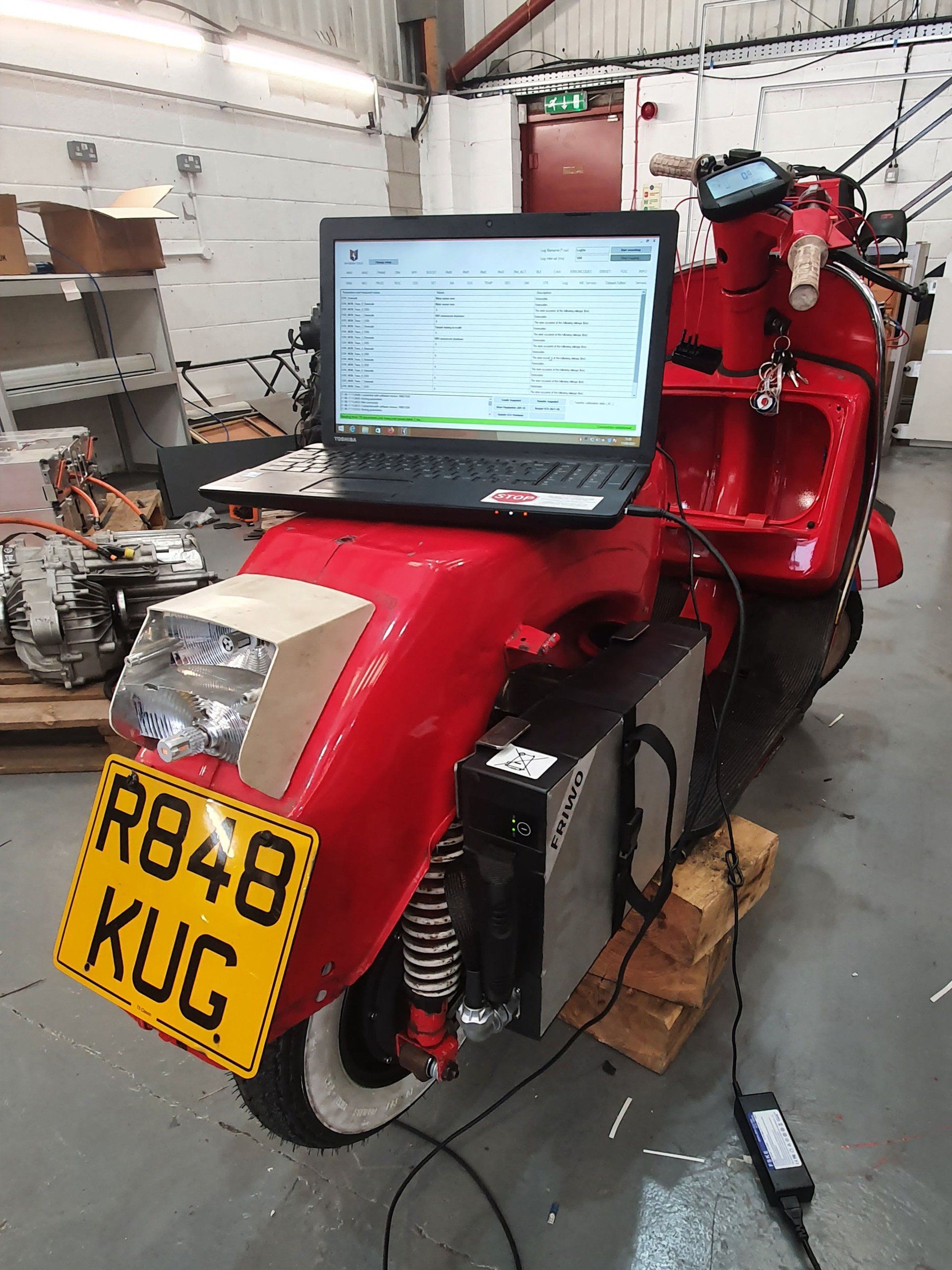 A red scooter with a laptop on top of it.