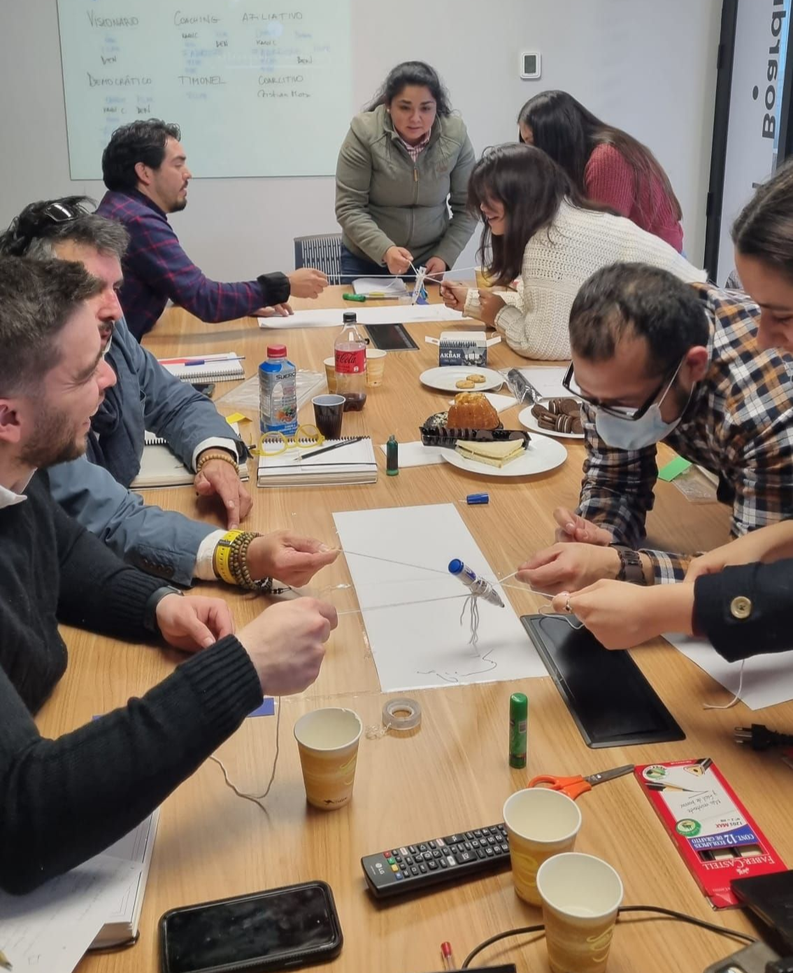 Un grupo de personas se reunió alrededor de una mesa, escribiendo en papeles y discutiendo ideas.