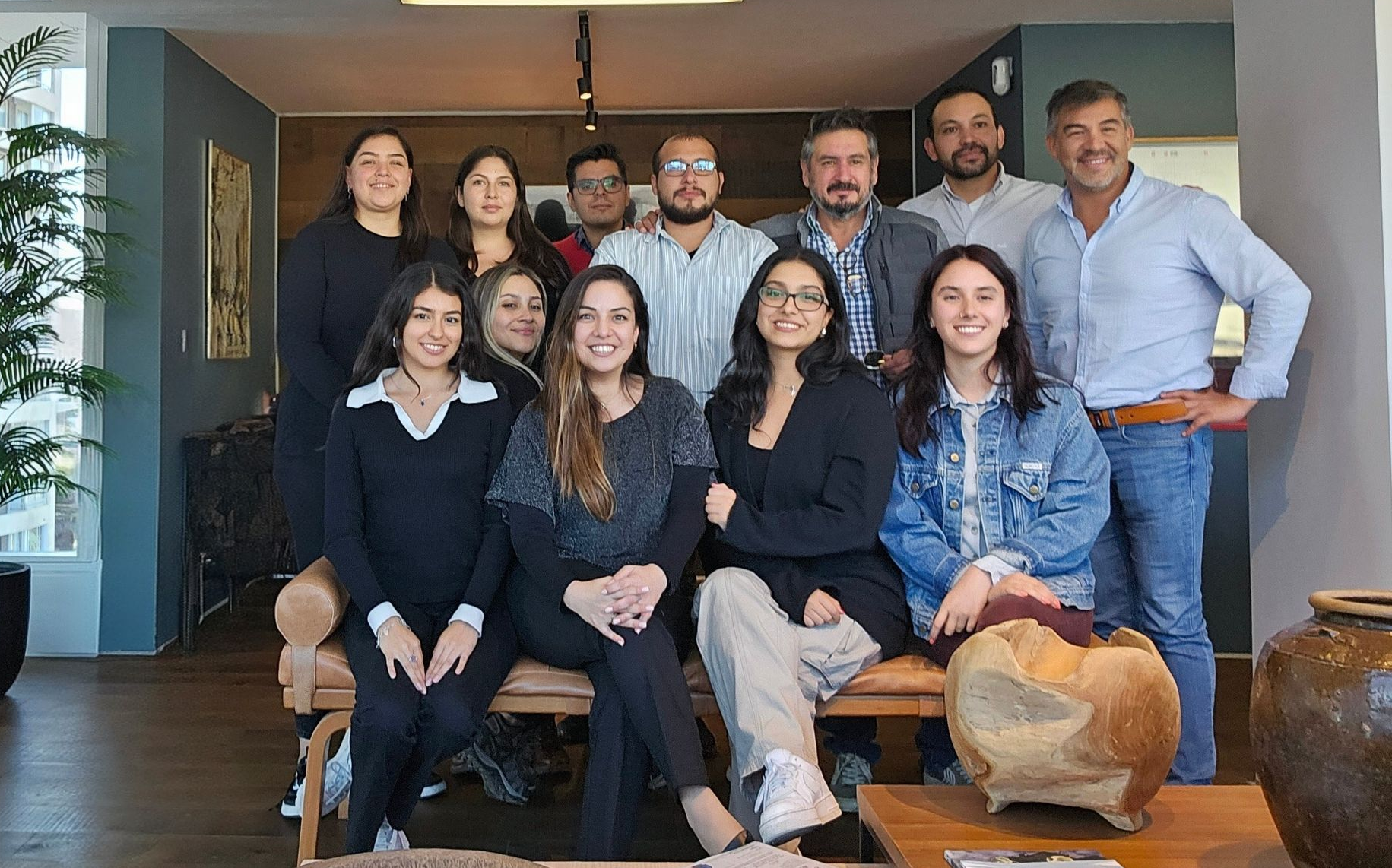 Diez personas posando juntas en una sala de estar moderna, sonriendo a la cámara.