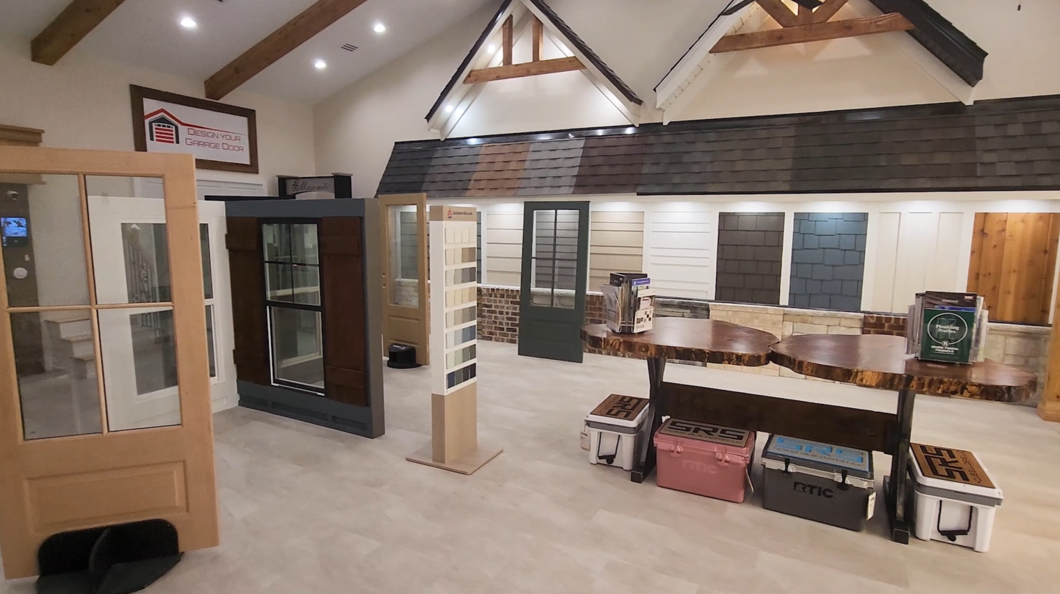 Interior showroom displays doors, shutters, and siding samples. The space has light wood and neutral tones.