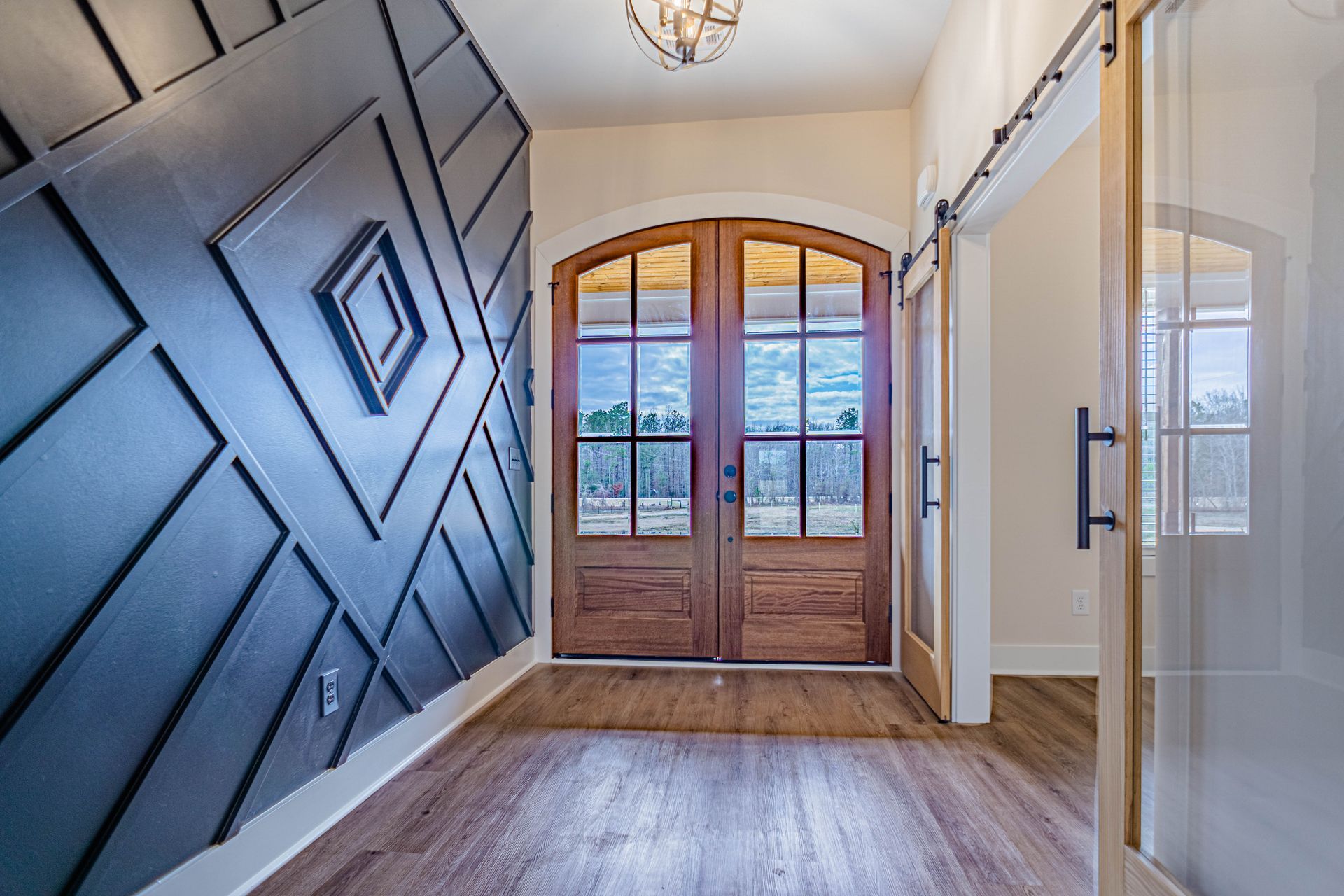 A hallway with sliding barn doors and a geometric wall.