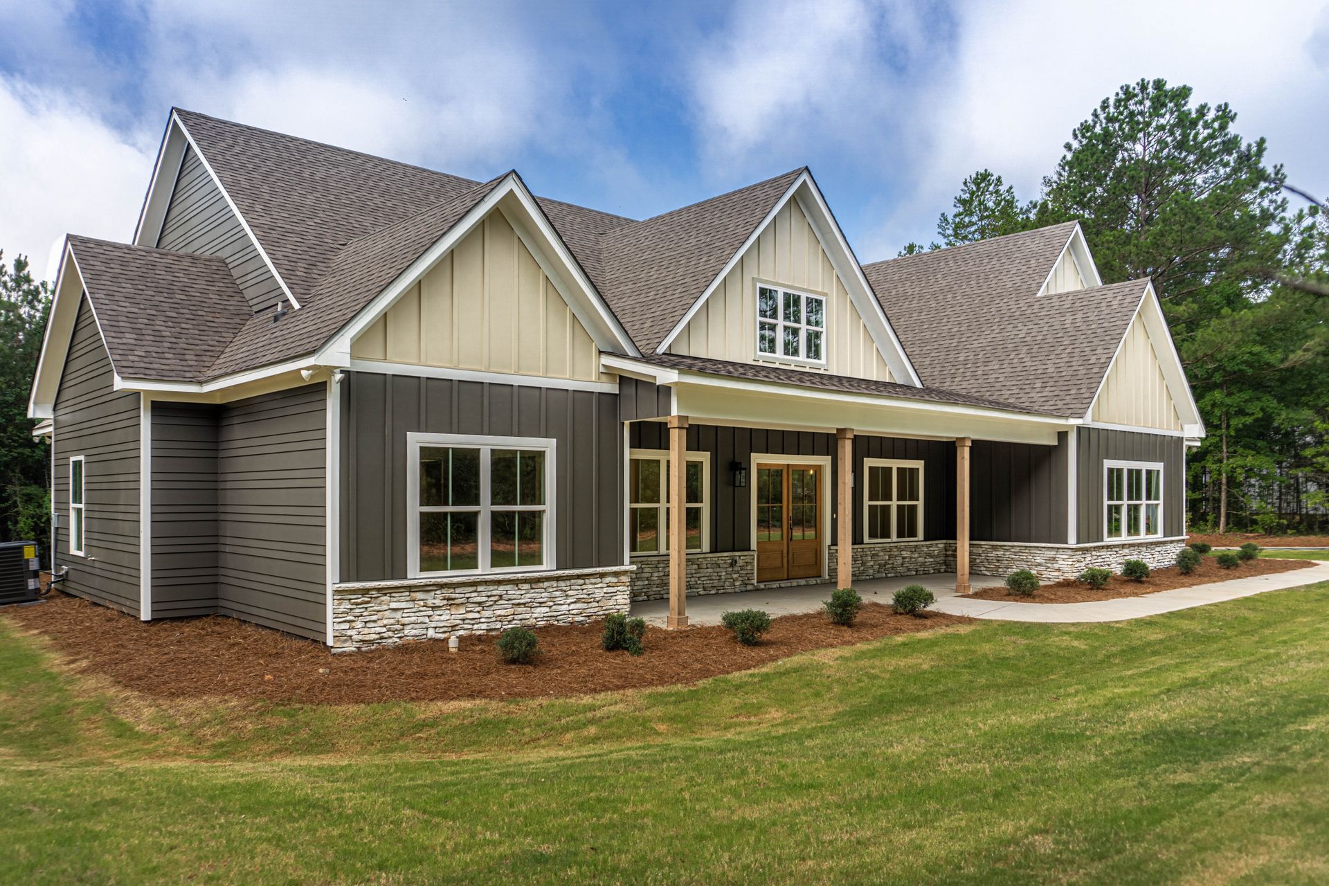 A large house with a large porch is sitting on top of a lush green field.