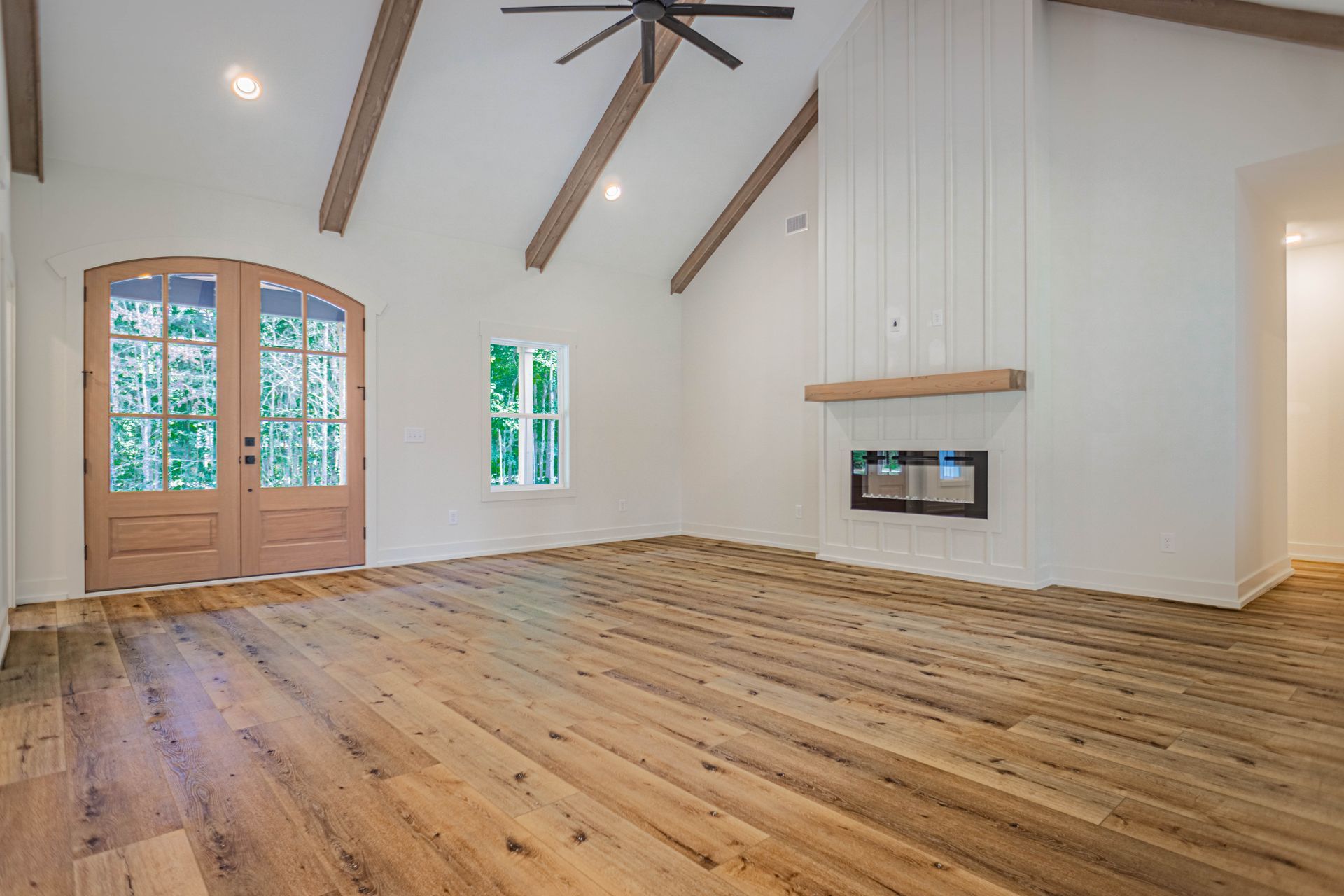 An empty living room with hardwood floors and a fireplace.