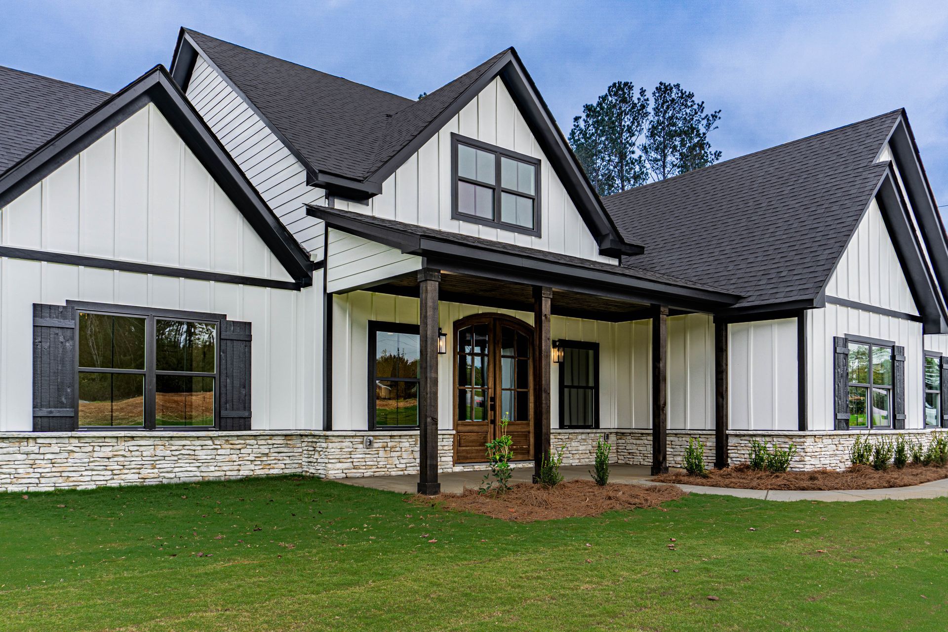 A large white house with a black roof and a porch.