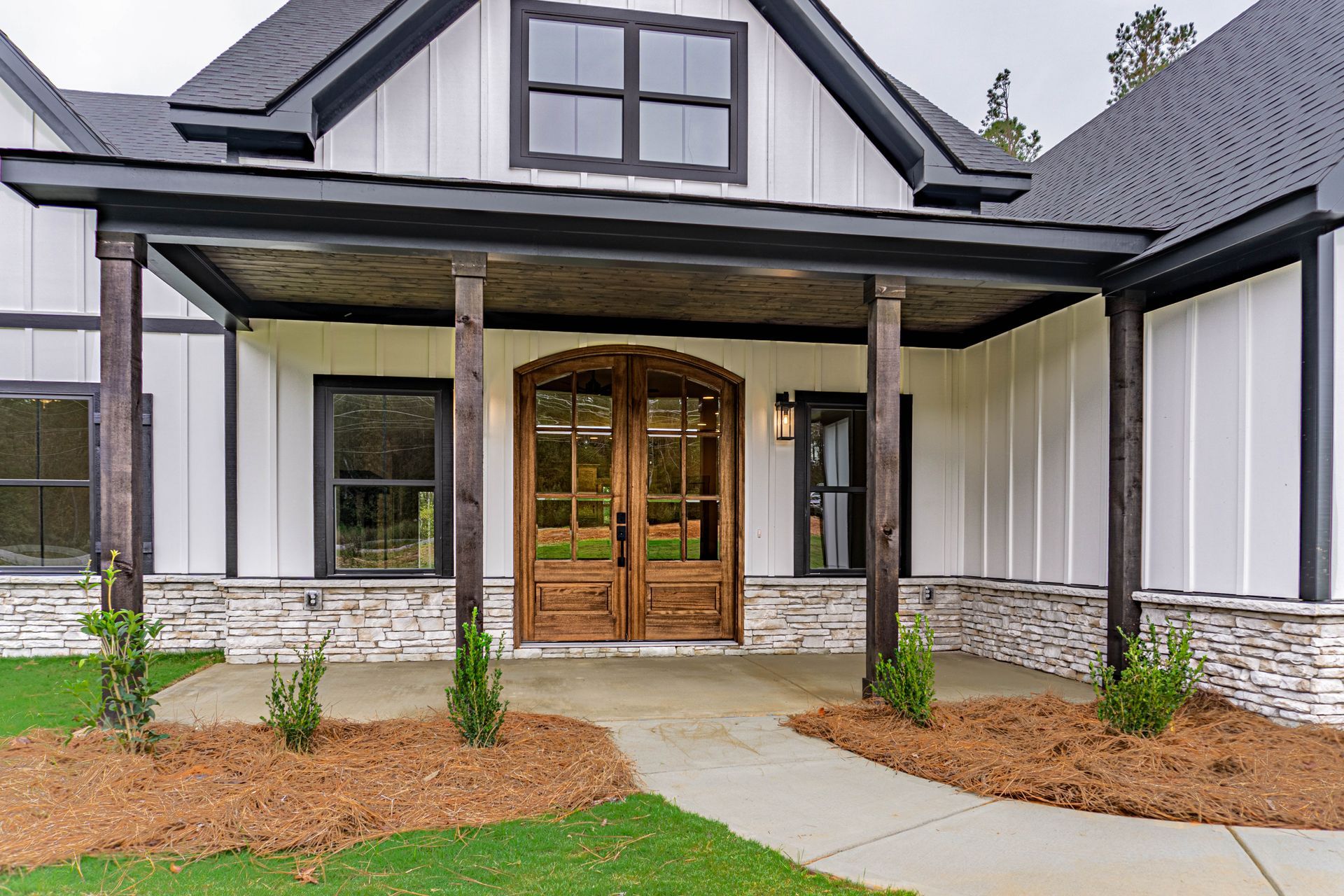 There is a porch with a wooden ceiling and a wooden door.