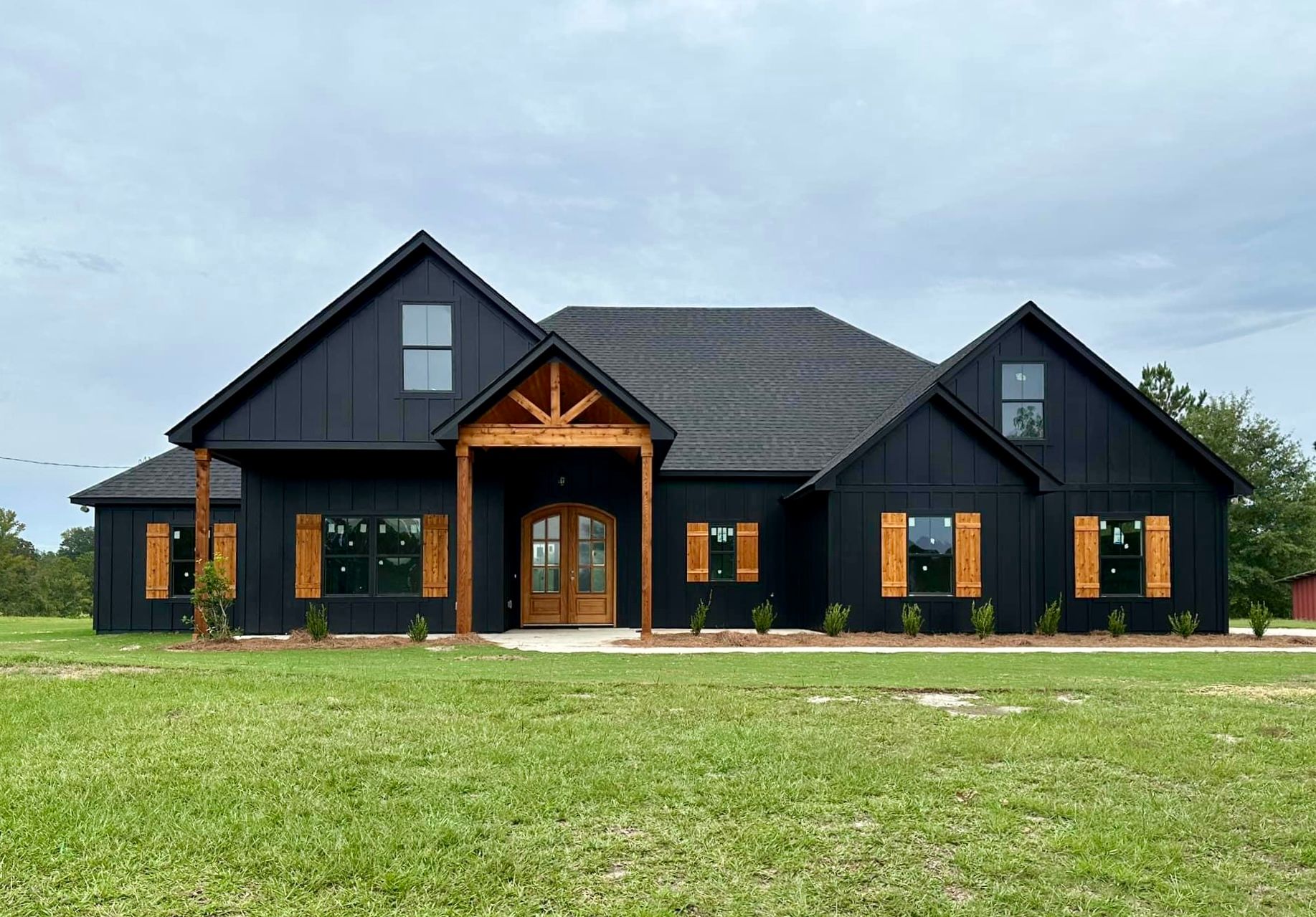 A large black house is sitting on top of a lush green field.