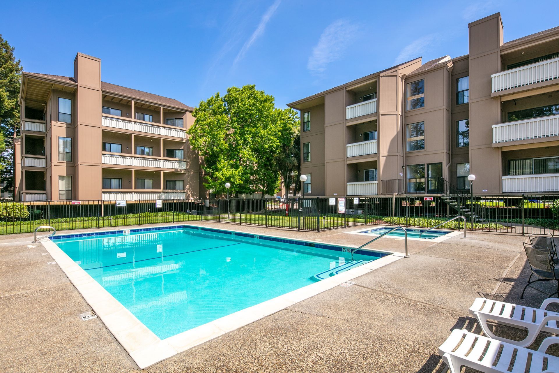 Apartment complex courtyard with a blue swimming pool and lounge chairs under a sunny sky at Vera West Valley in San Jose, CA.