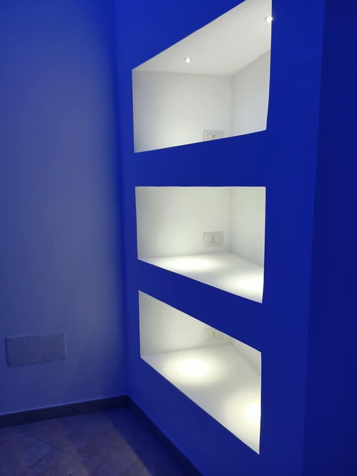Una parete blu con tre mensole bianche sopra