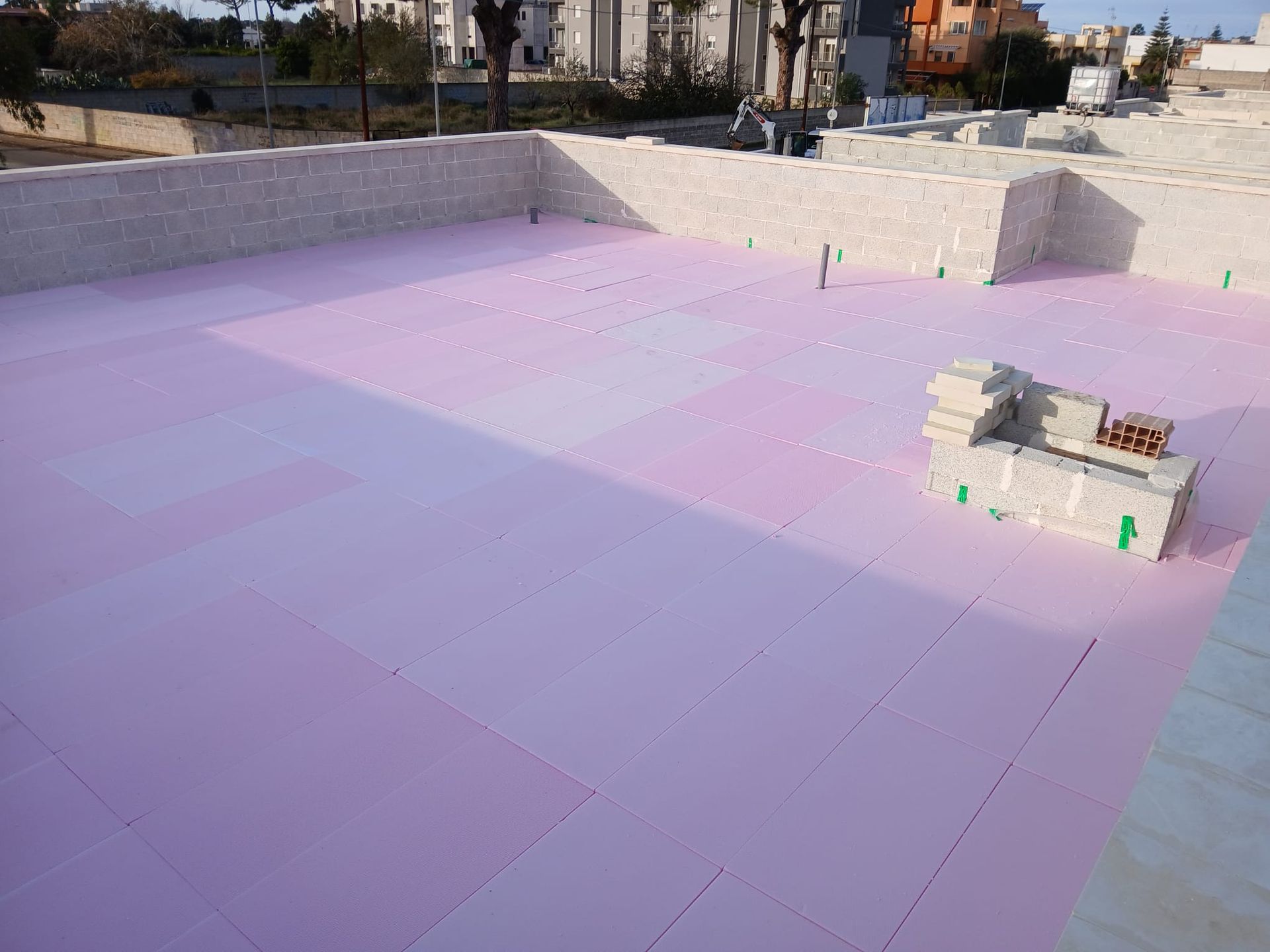 Un tetto rosa con un muro di mattoni sullo sfondo.