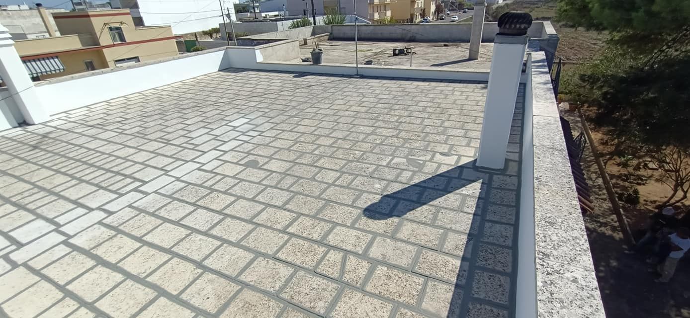 Un balcone con pavimento in mattoni e ringhiera bianca.