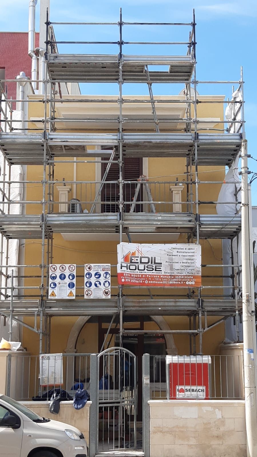 Un'auto è parcheggiata davanti a un edificio con sopra un'impalcatura.