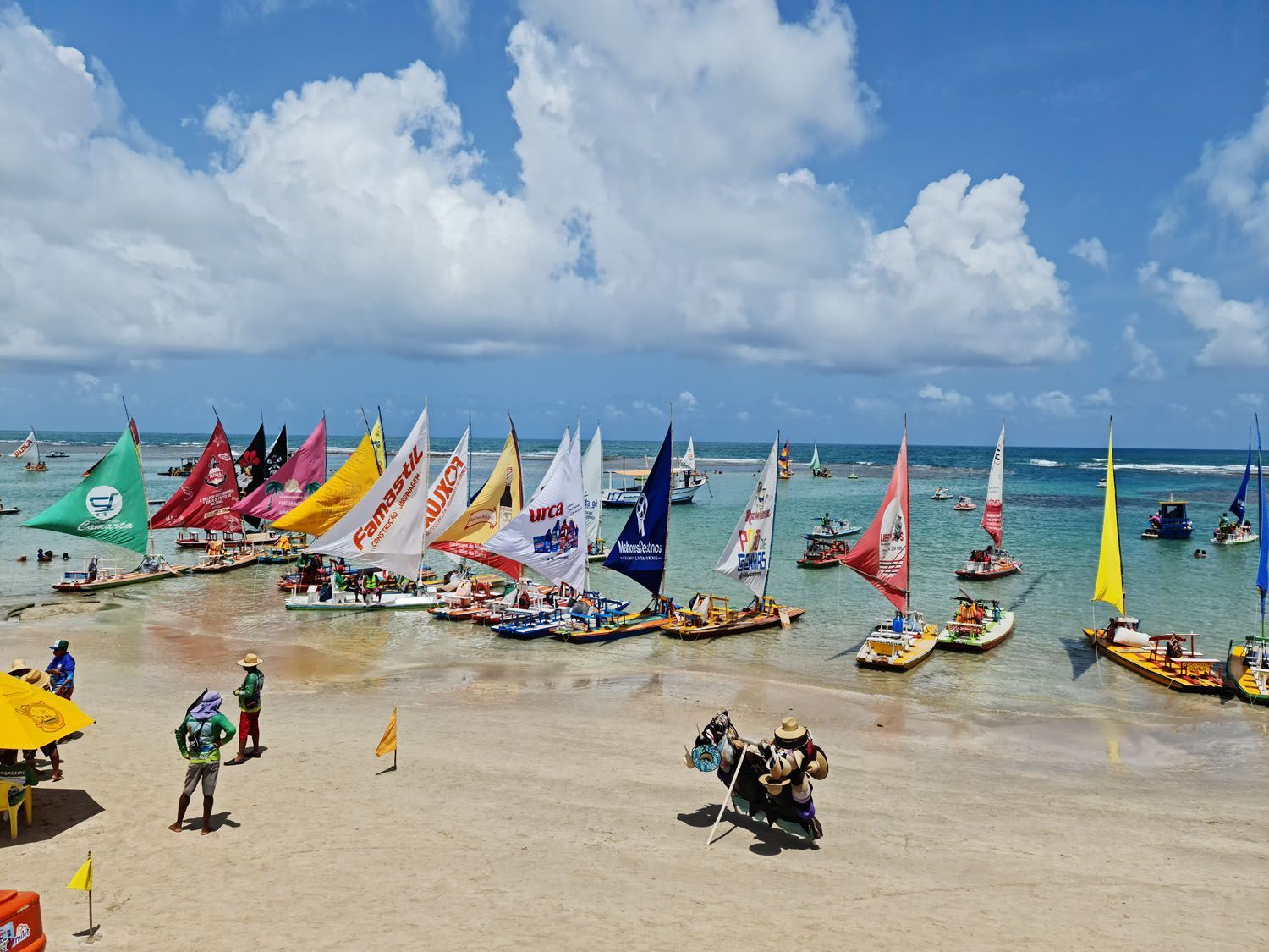 Uma praia com muitos veleiros na água