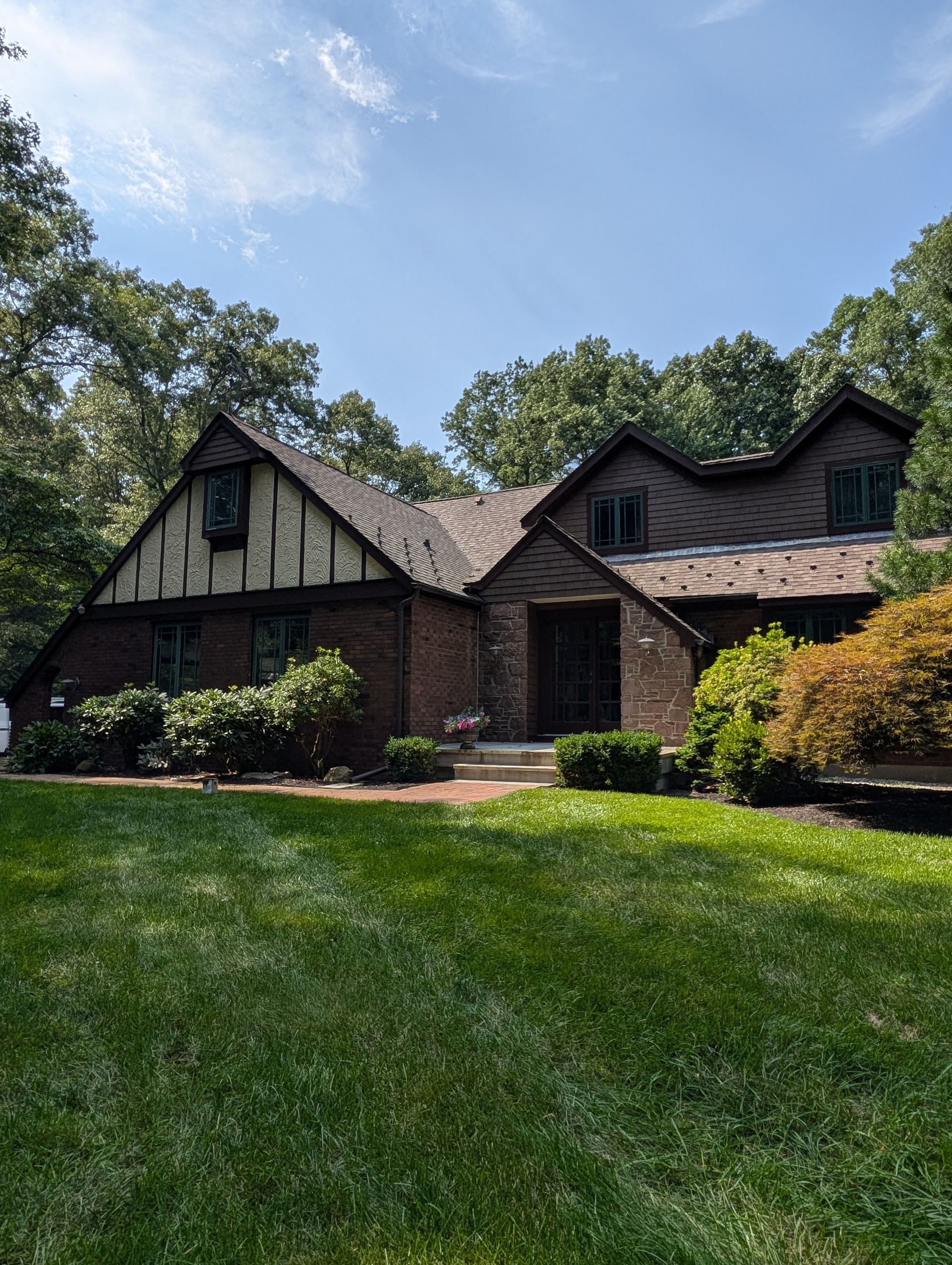 Brick house with steep gables and a green lawn under a blue sky
