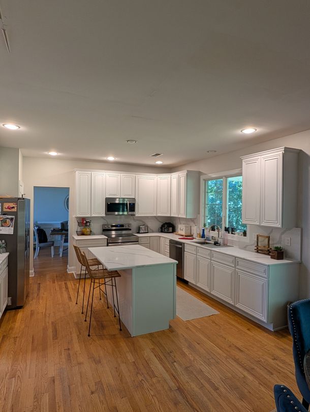 Bright kitchen with honey wood cabinets, white appliances, and tiled floor