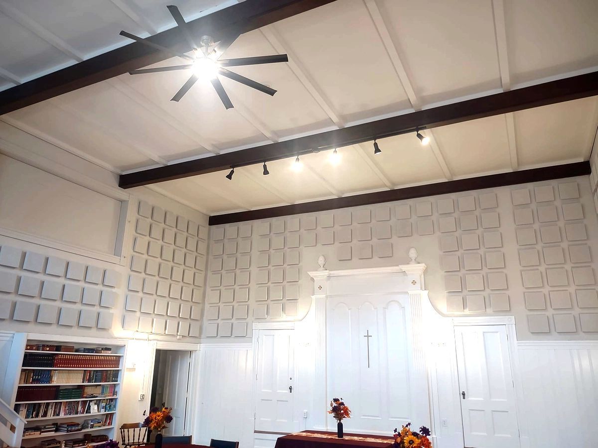 White paneled room with vaulted ceiling, ceiling fan, white double doors, and a bookshelf in the corner