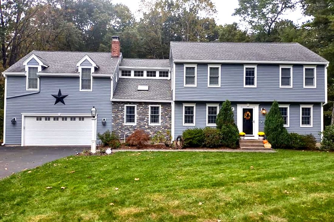 Gray two-story suburban house with white trim, attached garage, and a green lawn