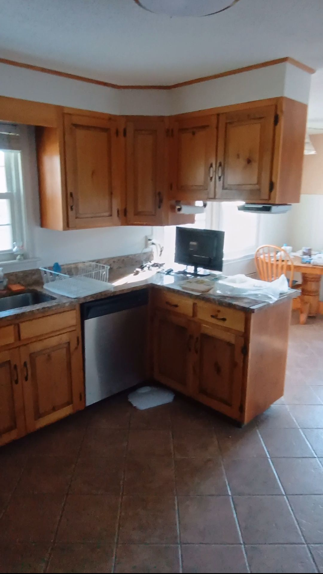 Wooden kitchen with L-shaped counters, tiled floor, and a window over the sink.