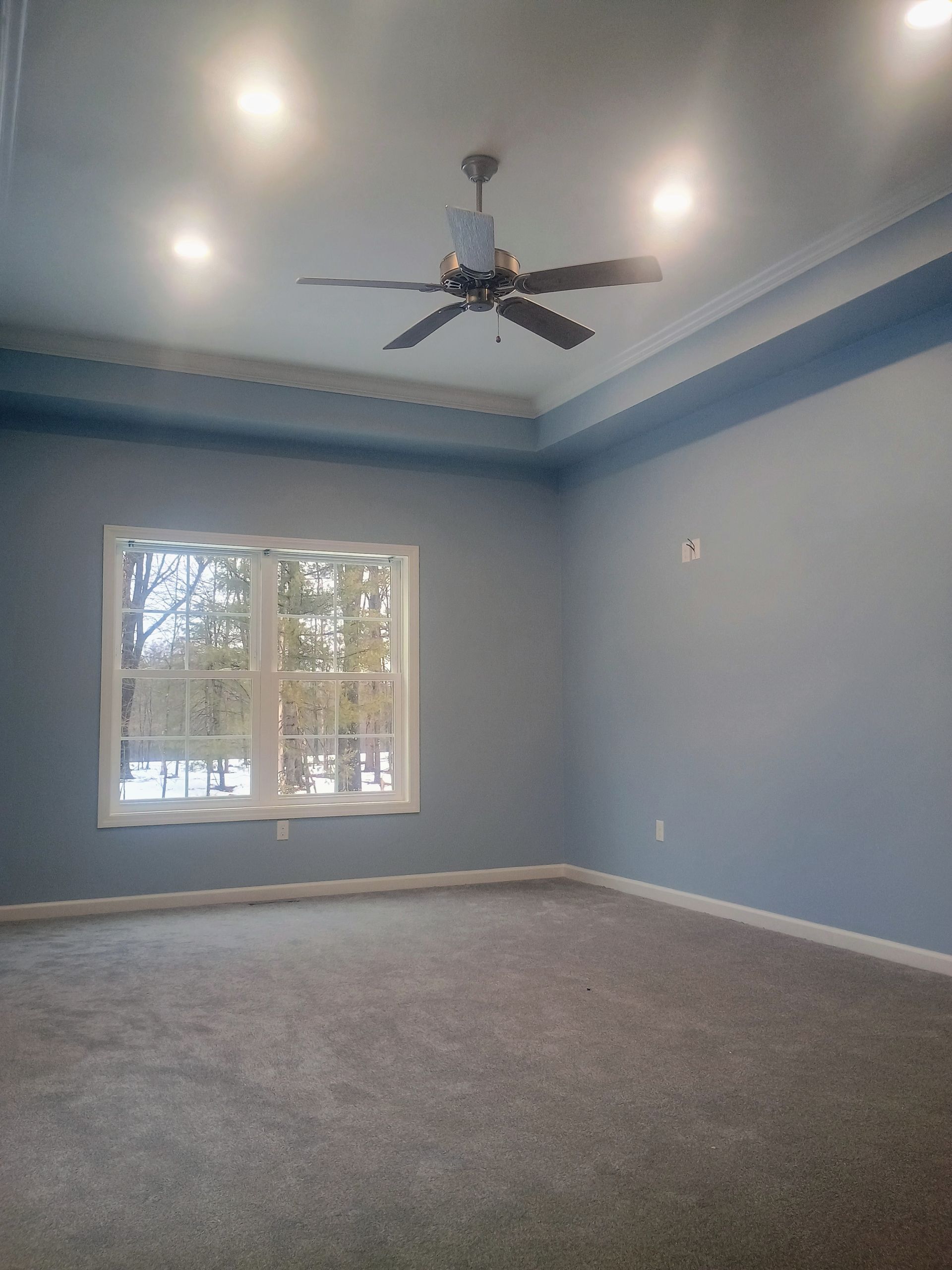 Empty light-blue room with carpet, window, recessed lights, and ceiling fan