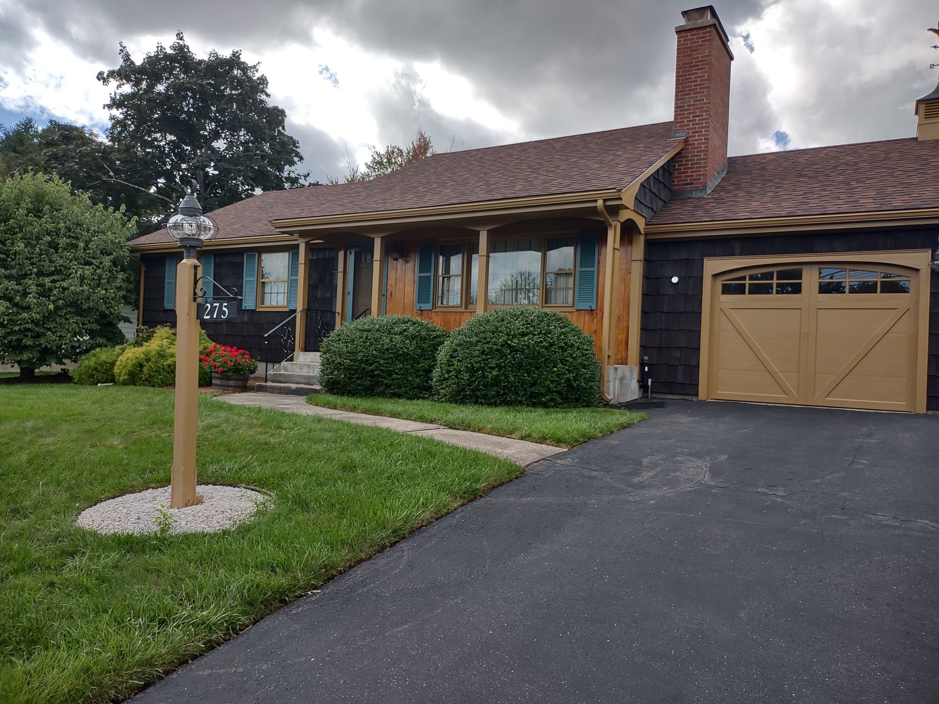 Single-story brick house with driveway, garage, front lawn, and cloudy sky