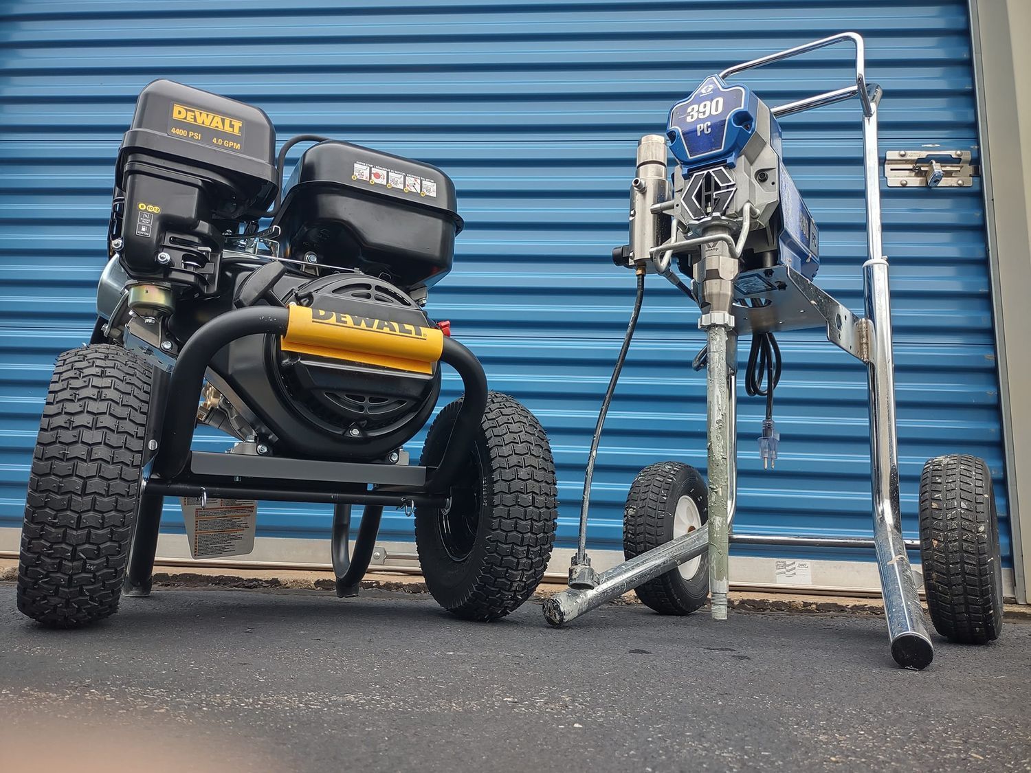 Two custom motorized off-road chairs and a walker parked on pavement before a blue garage door