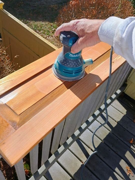 Person in white work clothes paints a staircase wall, pointing at the orange trim and steps.