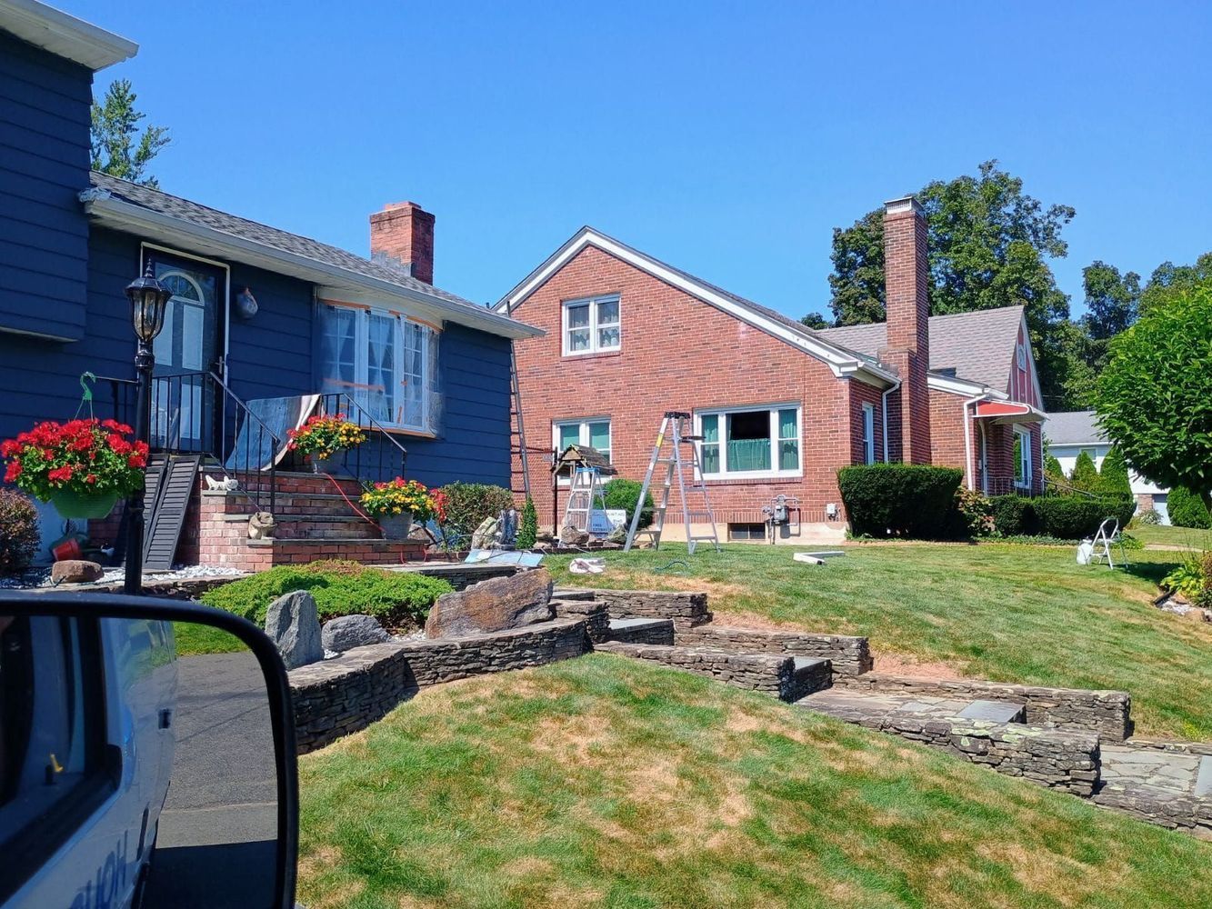 Residential houses with brick and blue siding, stone landscaping, and a grassy front yard on a sunny day