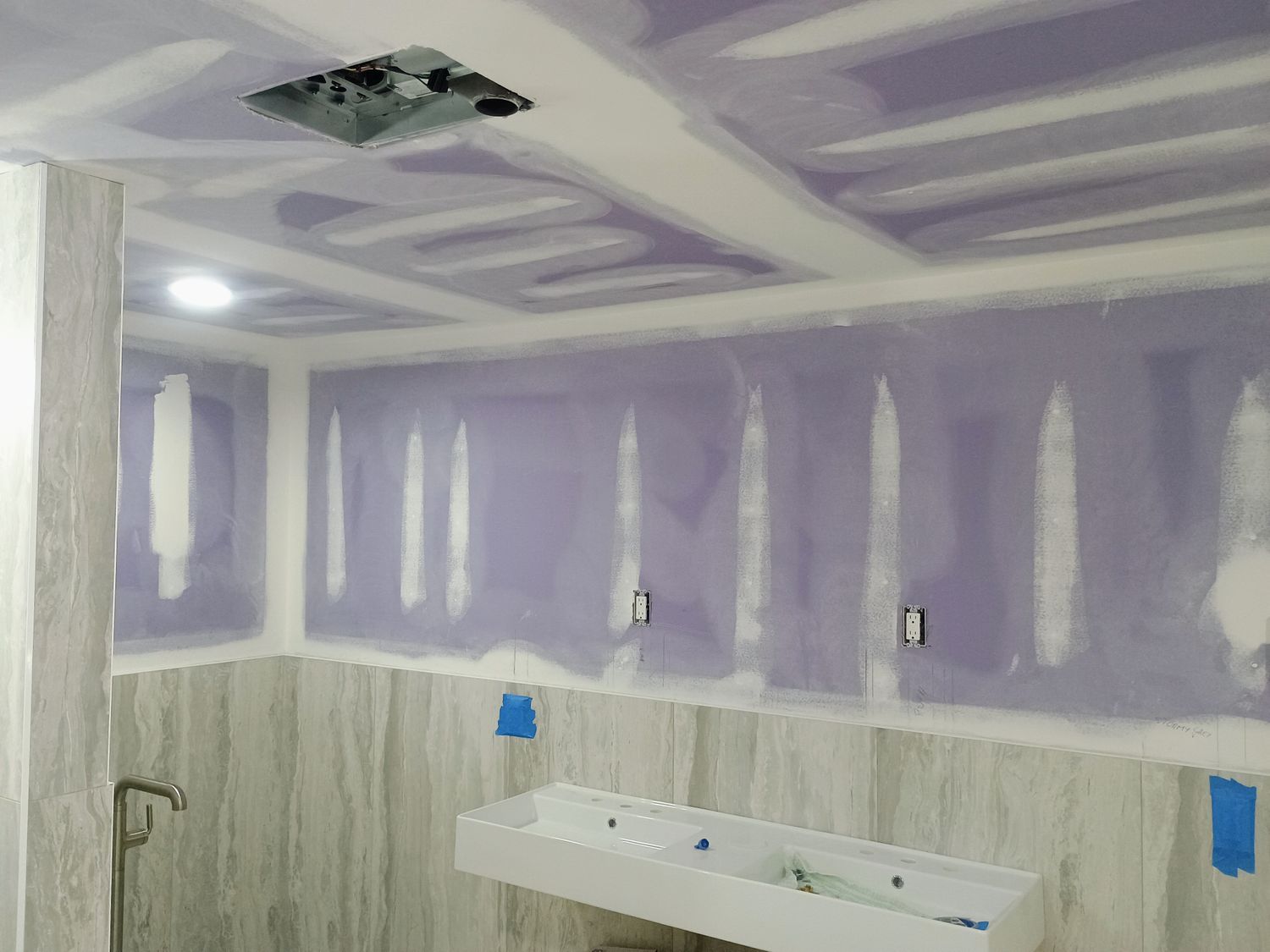 Partially renovated bathroom with purple drywall, sink, toilet, and ceiling fixture opening