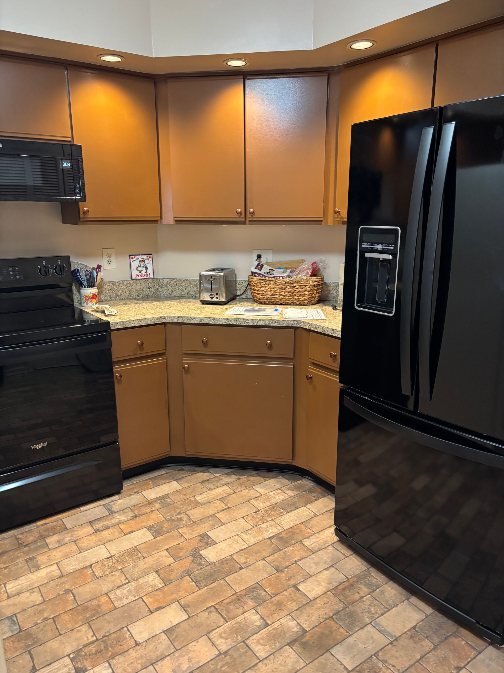 Modern kitchen with black appliances, brown cabinets, and tiled floor