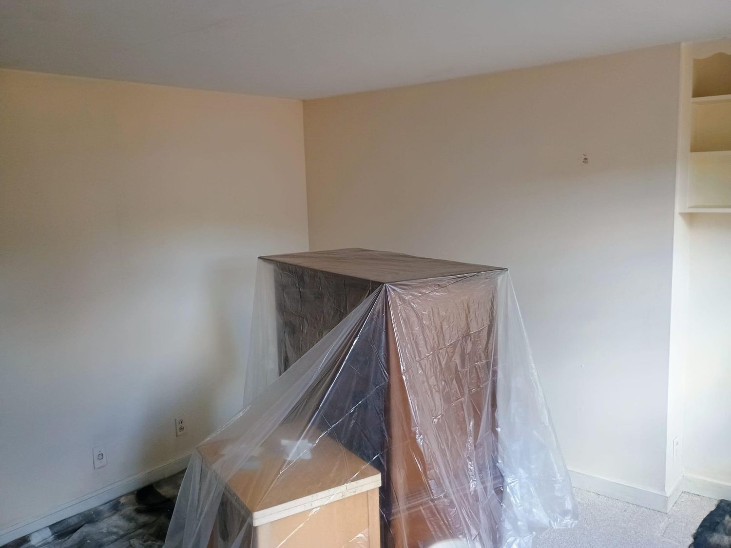 Plastic-covered furniture in an empty beige room