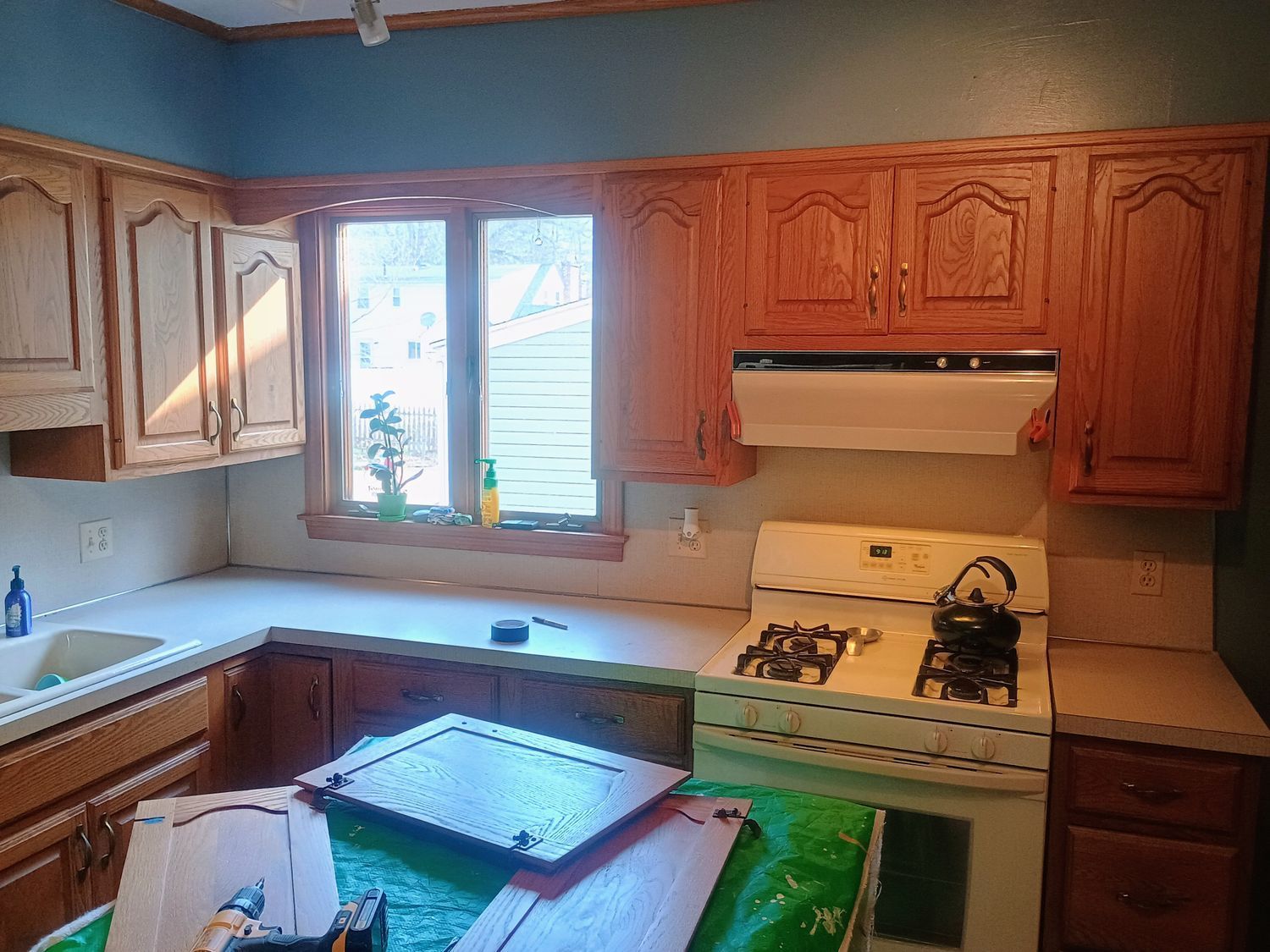 Wooden kitchen with white stove, sink under window, and central island with tray and green tablecloth