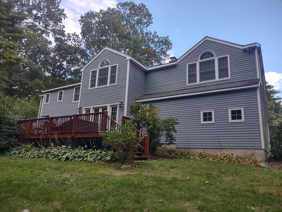 Gray two-story house with a red deck, white-trimmed windows, and a grassy yard
