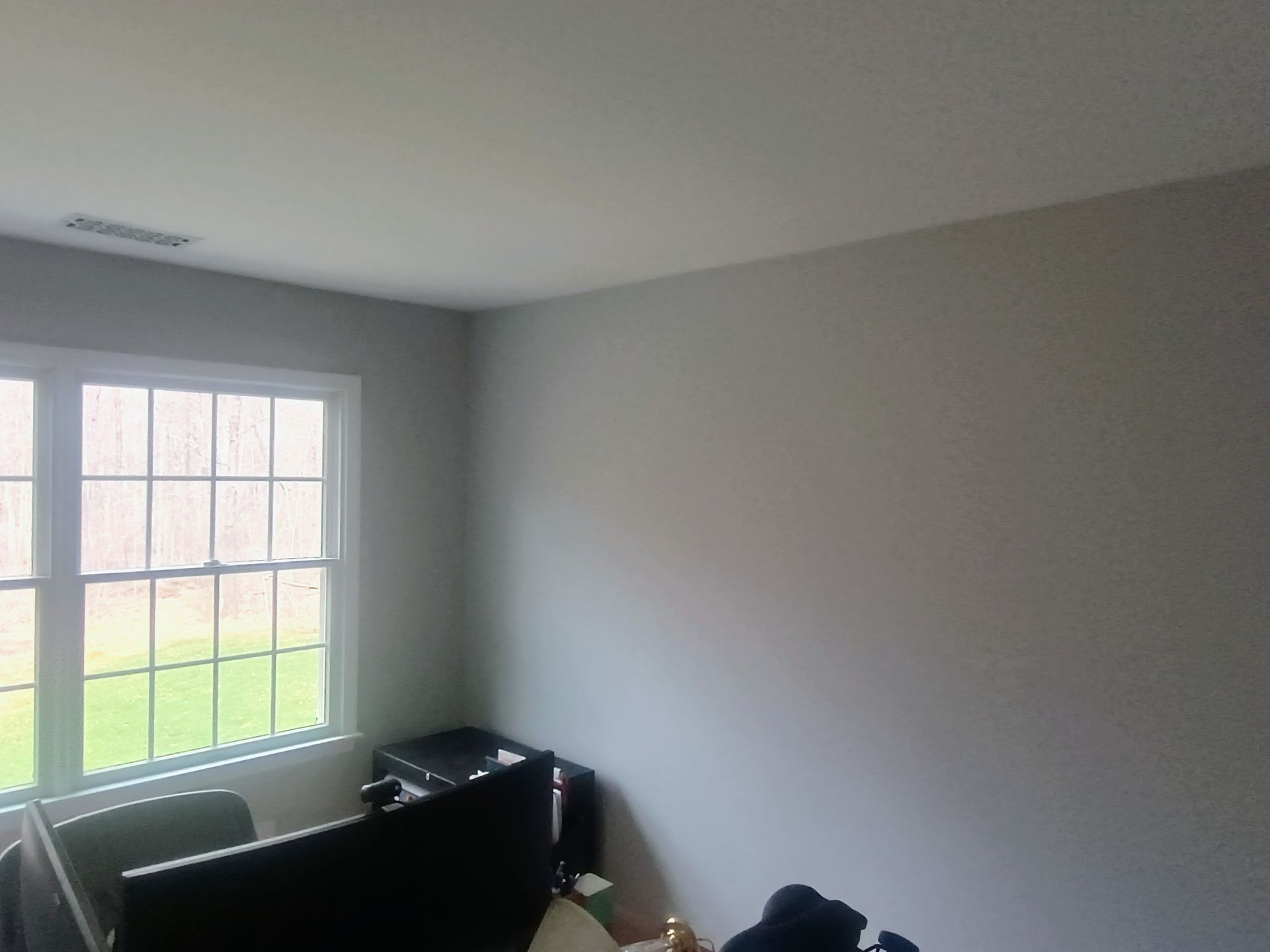 Small office room with a window, gray walls, and black furniture near the corner.