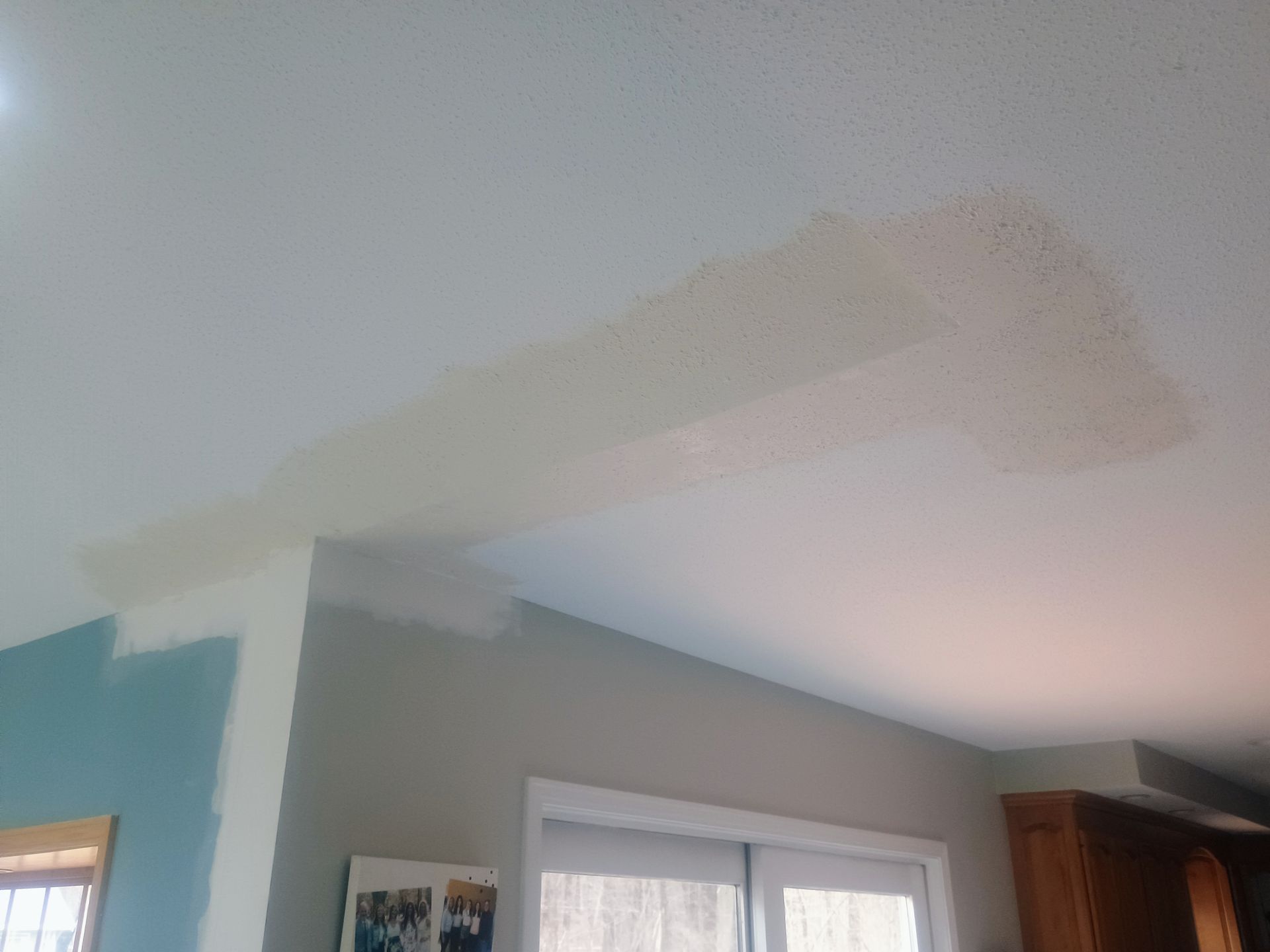 Living room ceiling with a large faded beige patch from a repair