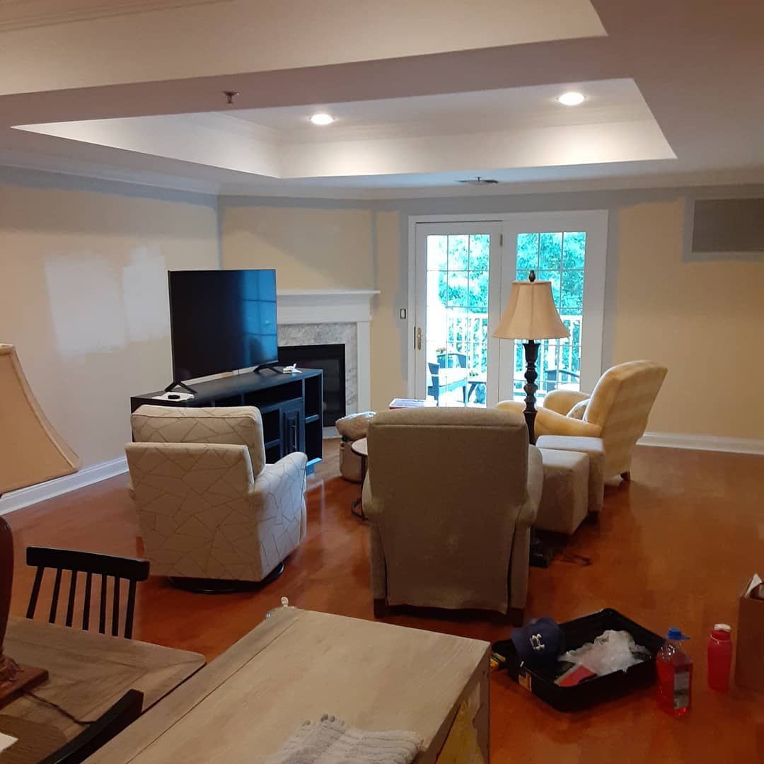 Living room with beige chairs, TV, fireplace, and glass doors to a bright patio
