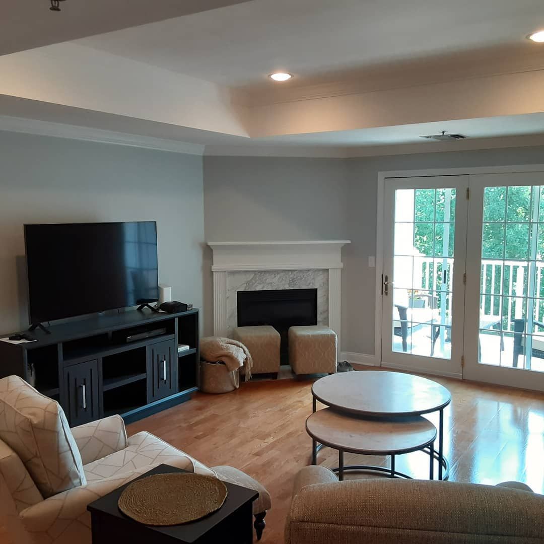 Bright living room with TV, fireplace, beige seating, and French doors opening to a patio.