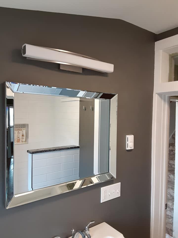 Bathroom mirror above sink with wall light and dark gray walls
