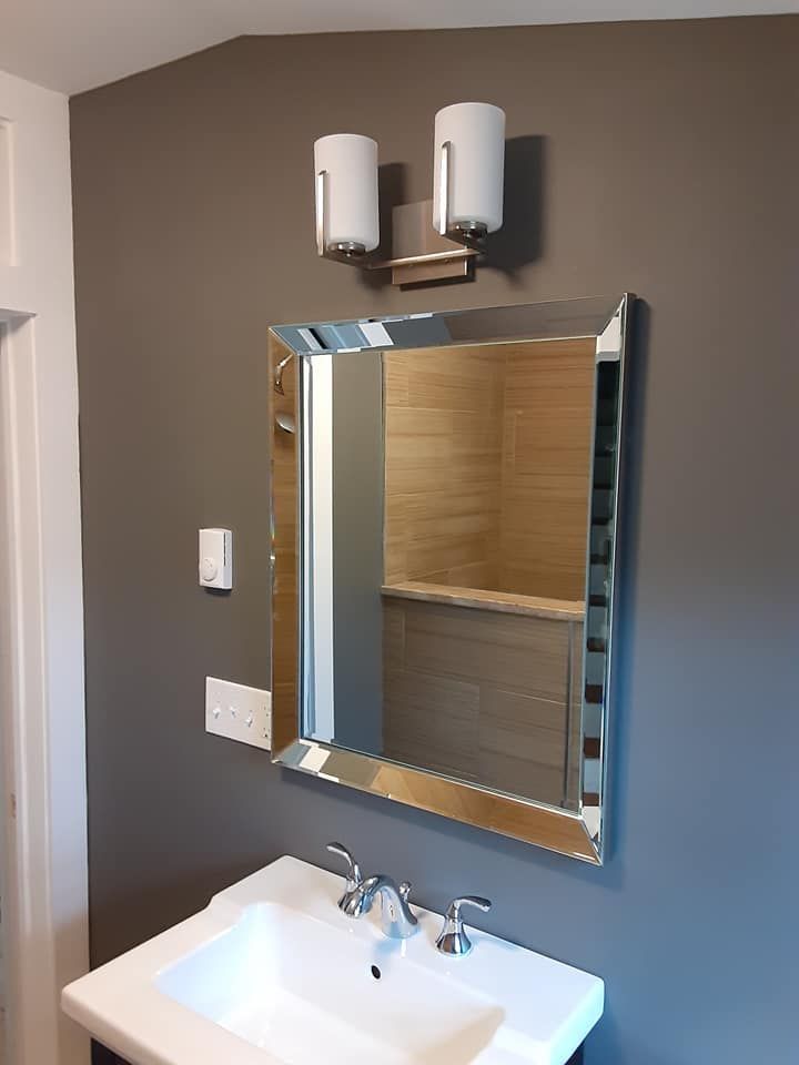 Bathroom vanity with mirror, sink, and two wall lights against a gray wall.