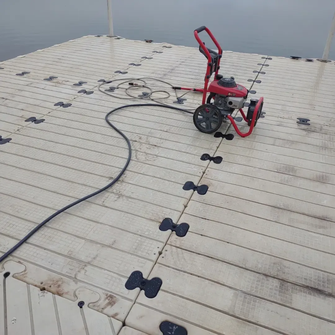 Red wheeled roof cleaning machine on a white roof with black anchor points and a hose attached.