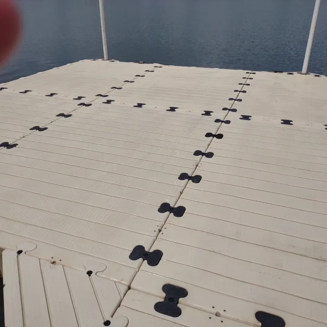 White interlocking floating dock sections with dark connectors on calm water under a gray sky