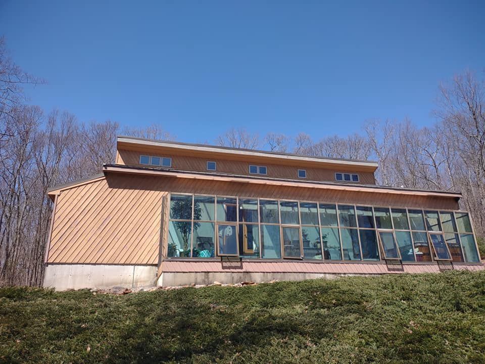Modern house with large glass windows on a grassy hillside under a clear blue sky