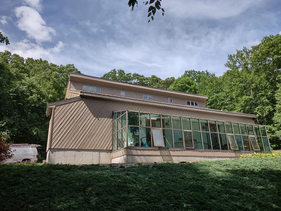 Modern house with large glass windows on a wooded hillside under a cloudy sky