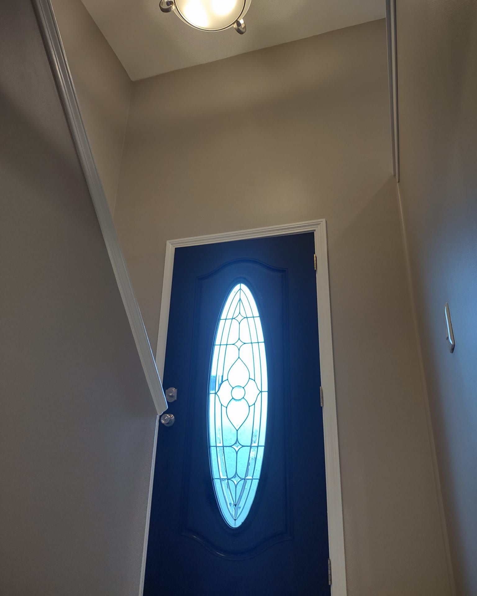 Hallway with a blue front door featuring an oval frosted glass panel and a ceiling light above