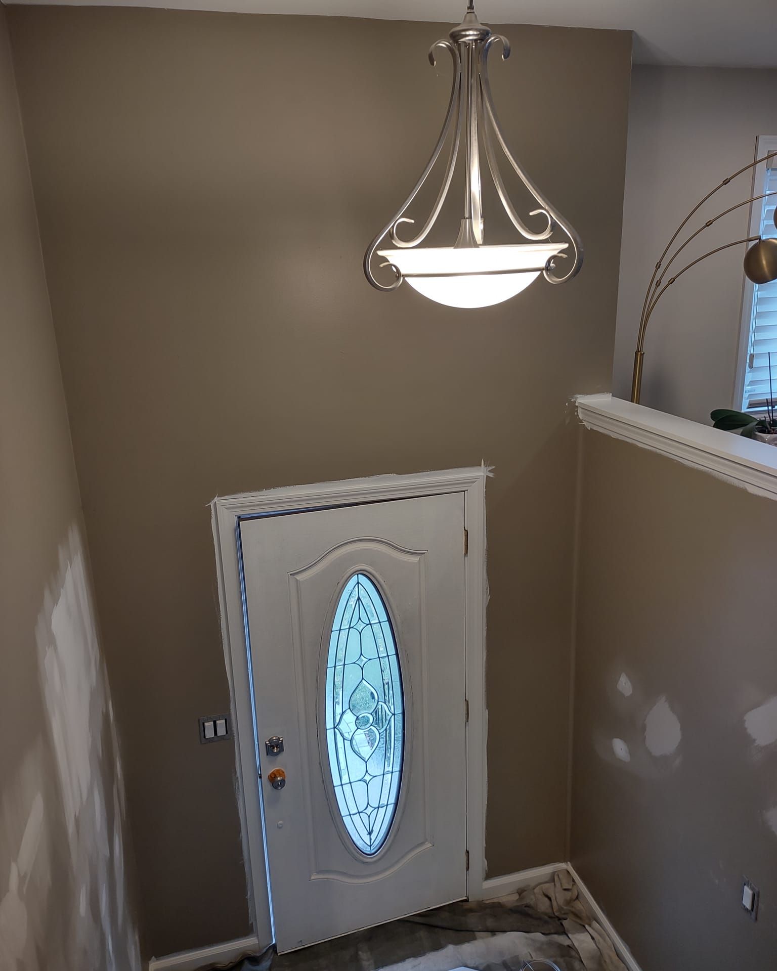 Stairwell with a white front door, hanging chandelier, and beige walls.