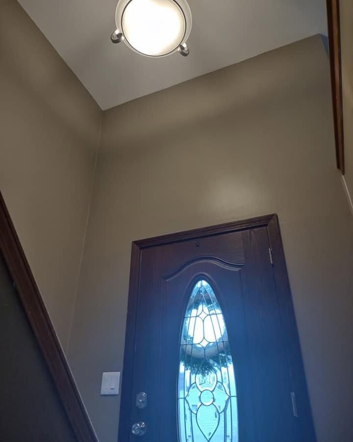 Front entryway with a dark wooden door, frosted glass panel, and beige walls under a ceiling light.