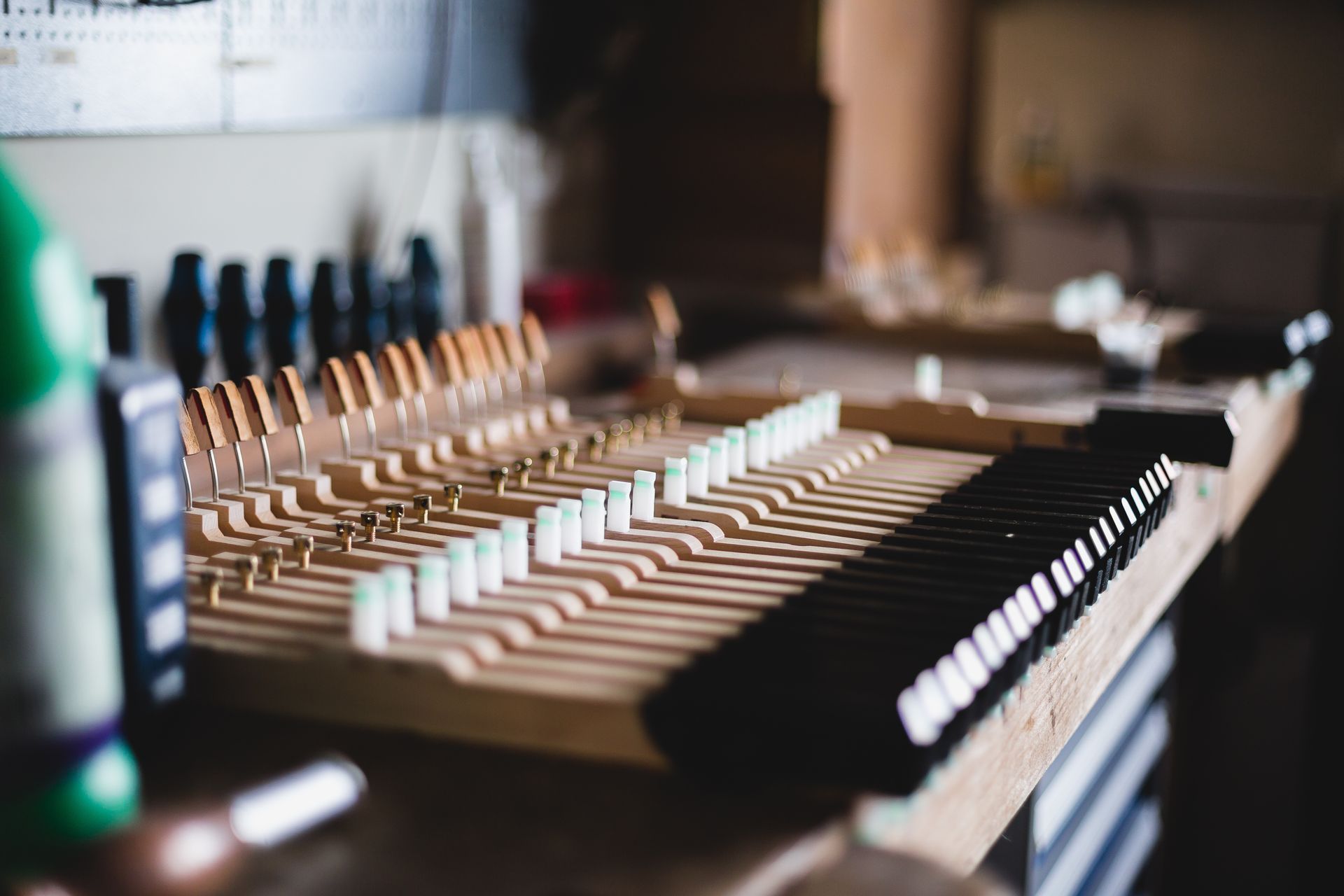 Row of white and black piano keys on a wooden keyboard, softly lit in a studio.