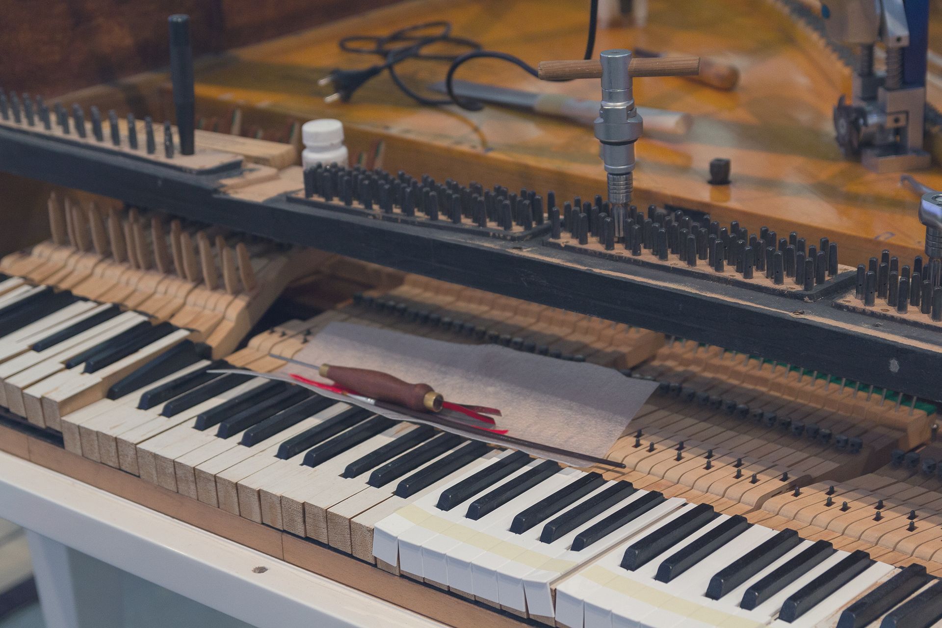 Piano mechanism with hammers and strings exposed above the keys, showing the inner workings of an upright piano