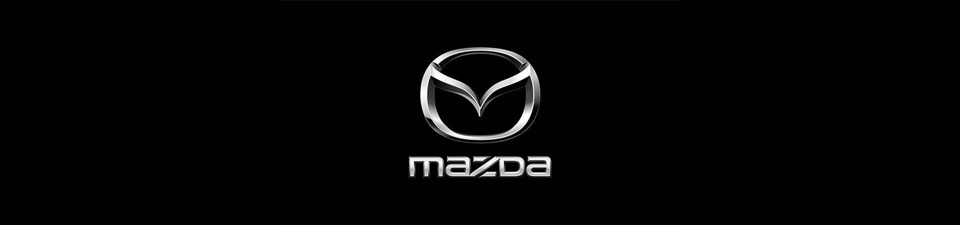 Das Mazda-Logo in metallischem Silber mittig auf schwarzem Hintergrund, darunter der Schriftzug „mazda“ in weißer Schrift.