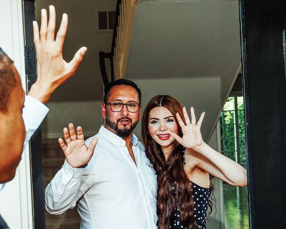 Builder waving goodbye to couple in their renovated home