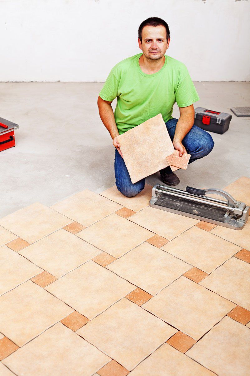 man in green shirt holding an orange floor tile
